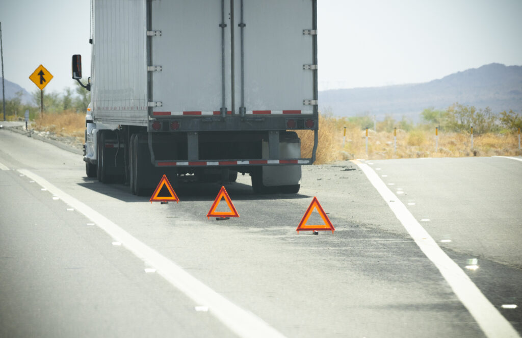 Disabled trailer pulled to the roadside with reflective warning triangles placed behind it, representing trailer repair service.