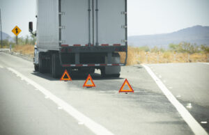Disabled trailer pulled to the roadside with reflective warning triangles placed behind it, representing trailer repair service.