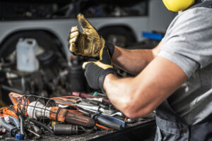 Technician in protective gear gives a thumbs-up beside a tool-filled workbench, representing mobile service on heavy equipment.