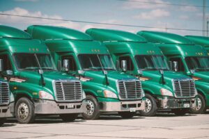 A fleet of green trucks in a parking lot.